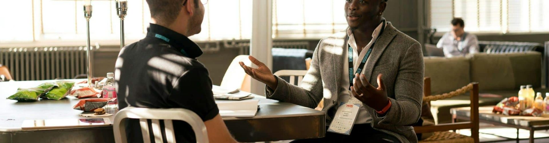 pexels-photo-935949-935949 Two men having a casual discussion in a bright indoor setting, highlighting mentorship.